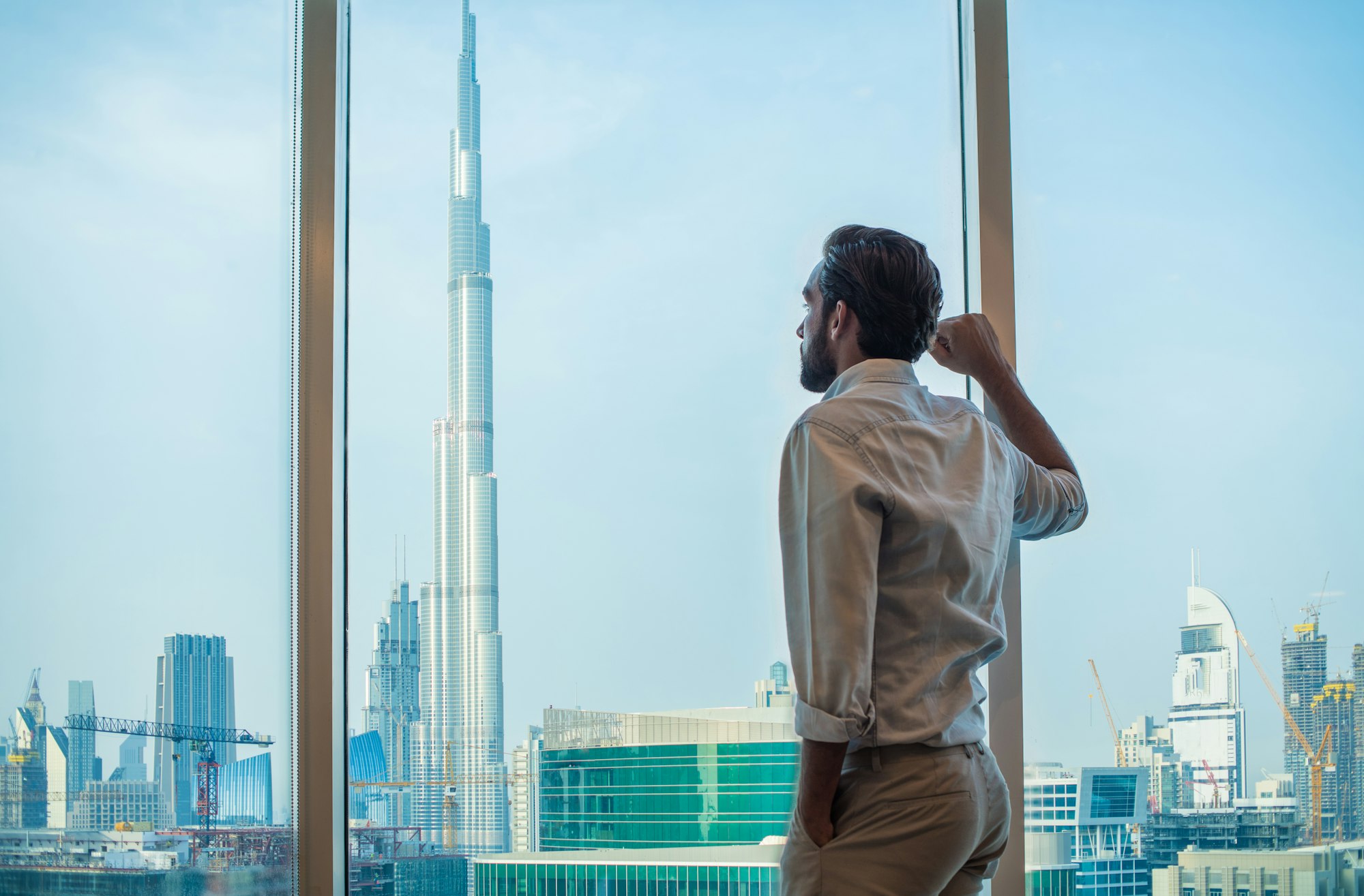 Businessman gazing through window with city view, Dubai, United Arab Emirates