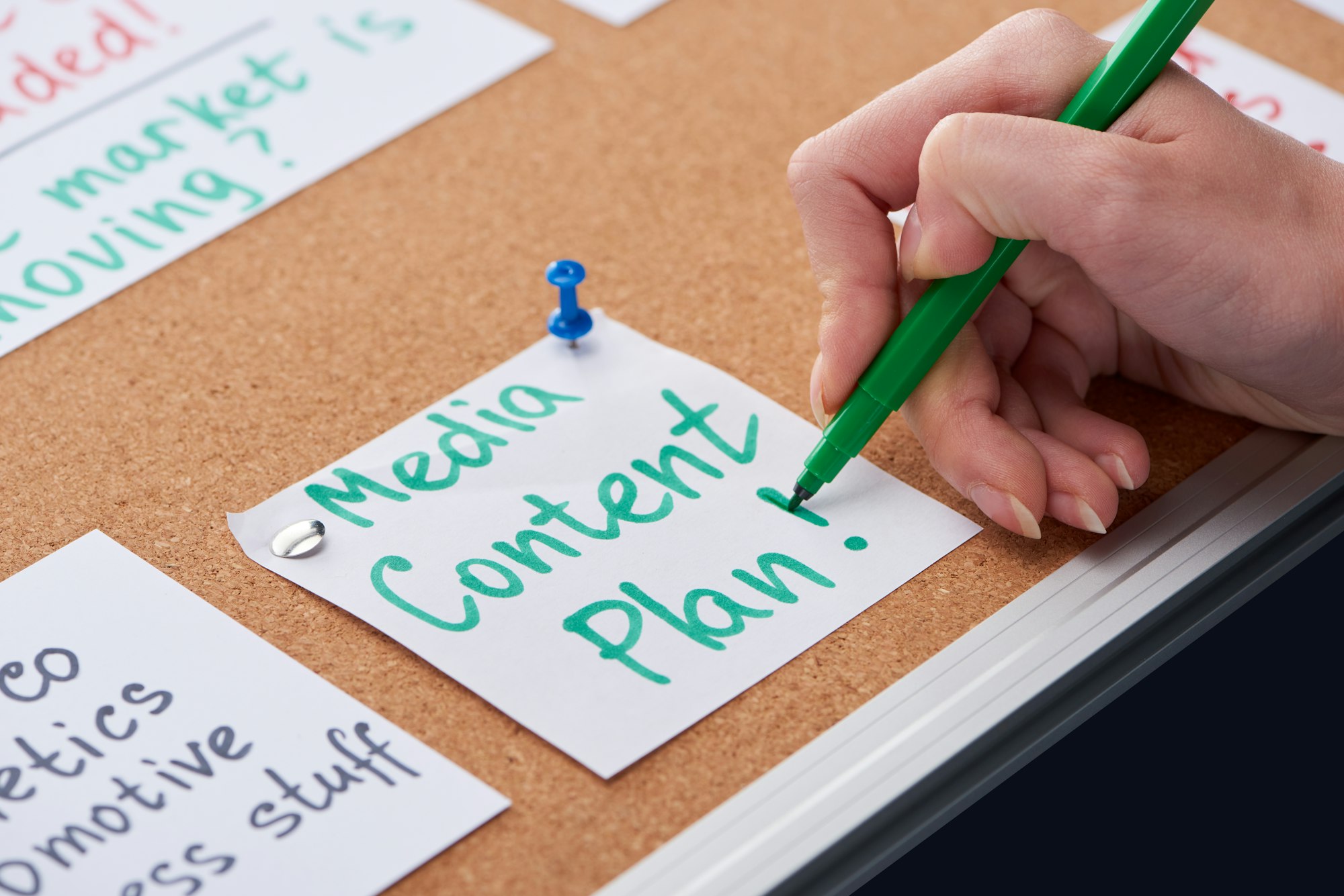 cropped view of woman writing media content plan inscription on card pinned on cork board